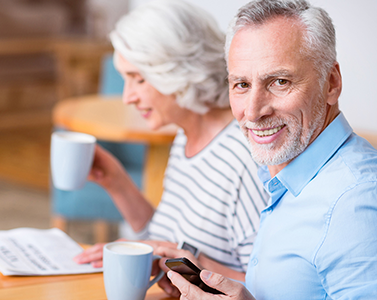 homme qui boit une tasse de café en souriant