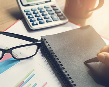 Main, calepin, crayon et calculatrice sur un bureau