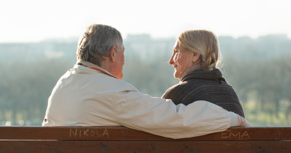 Couple à la retraite se sourient assis sur un banc de parc