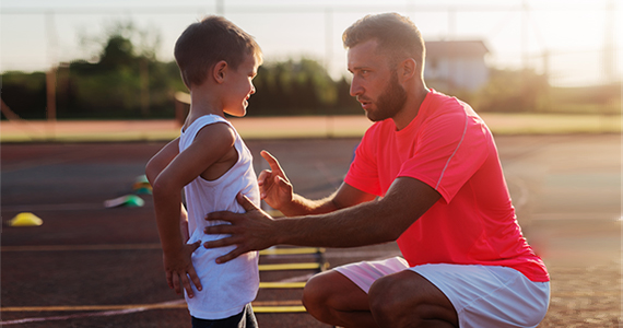 Un enseignant d’éducation physique donnant des consignes à un enfant.