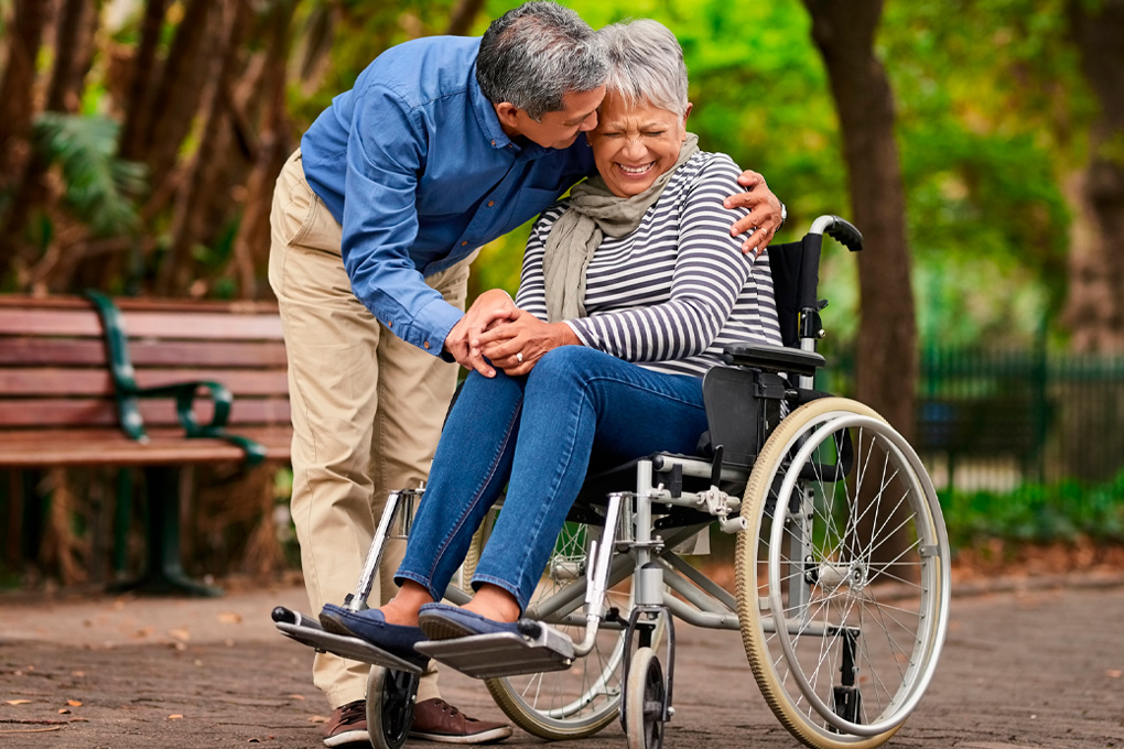 Photo d'un homme qui prend dans ses bras une femme assise dans un fauteuil roulant