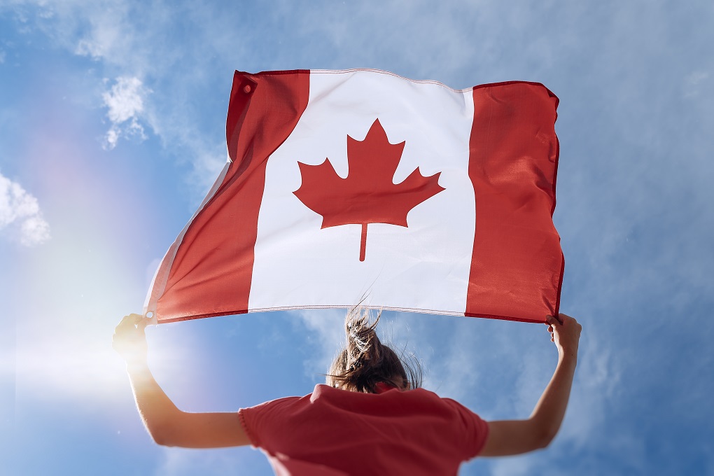 Une femme résidente du Canada tient un drapeau canadien dans ses mains.